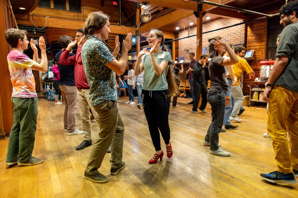 Swing dancers high-five while other couples dance around them